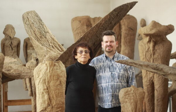 To personer står blant flere skulpturer. Foto.