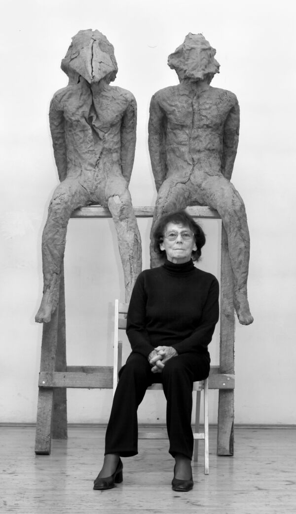Kunstneren Magdalena Abakanowicz sitter foran to skulpturer. Foto.