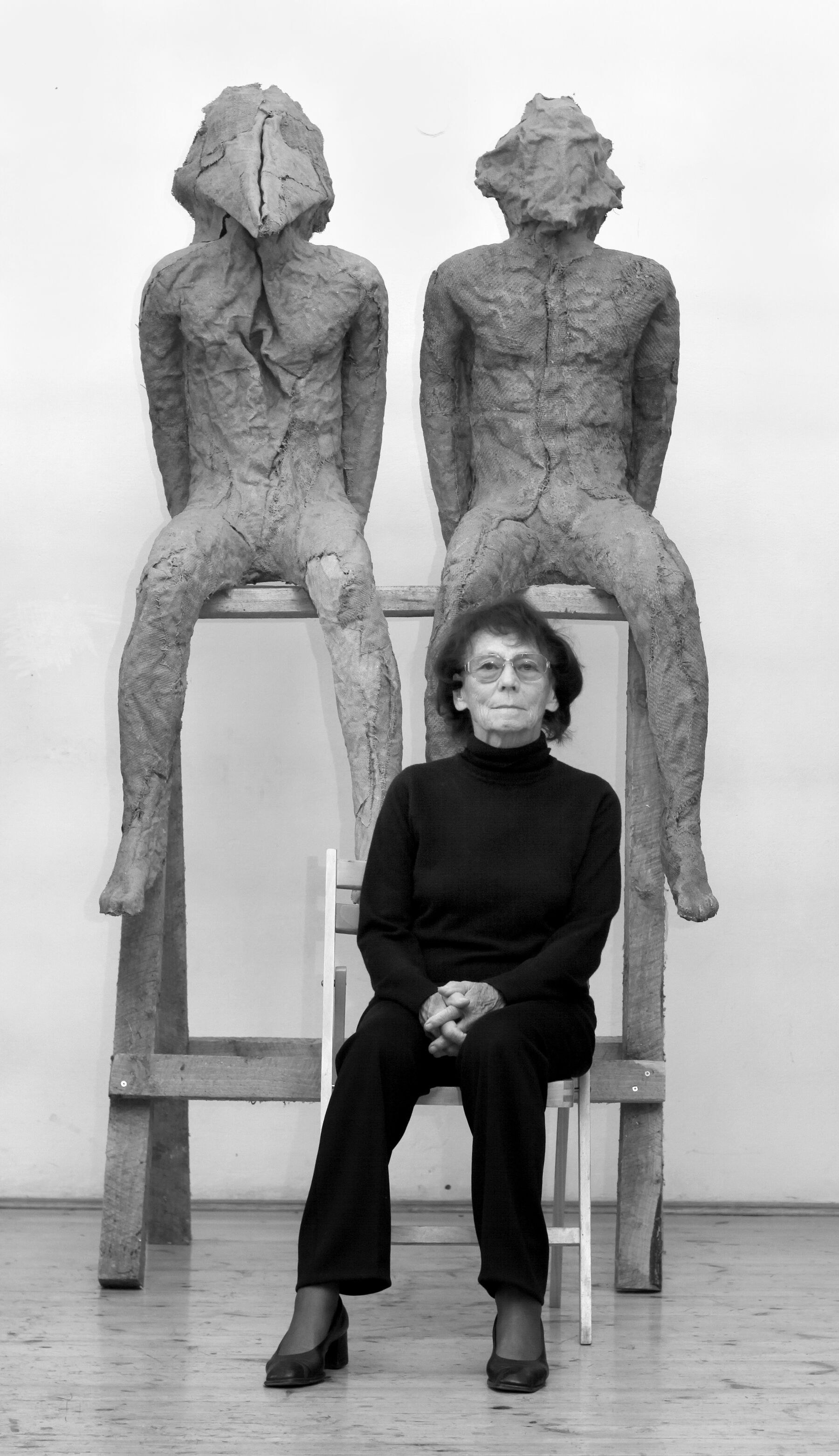 Kunstneren Magdalena Abakanowicz sitter foran to skulpturer. Foto.