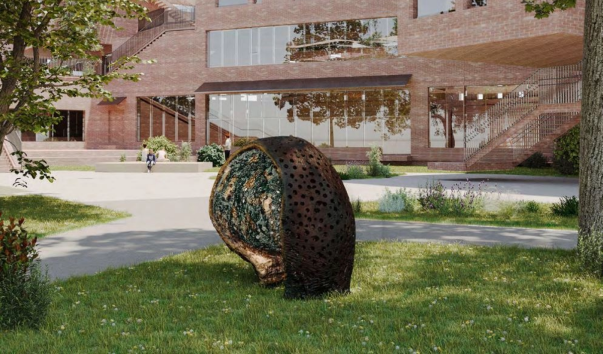 Kunstverk plassert i skolegården, med skolen og barn i bakgrunnen. Foto.