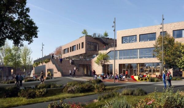 Skolen og skolegården med grønt landskap i forgrunnen og skolen i bakgrunnen. Foto.