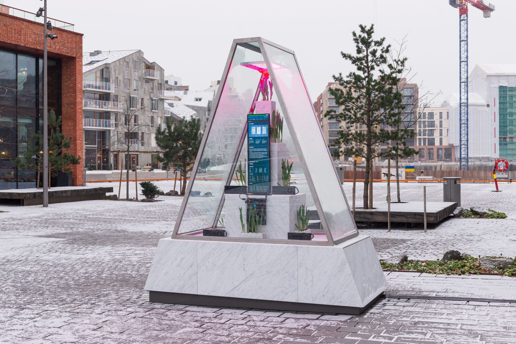 En trekantet skulptur laget av marmor, glass og elektronikk inni. Foto.