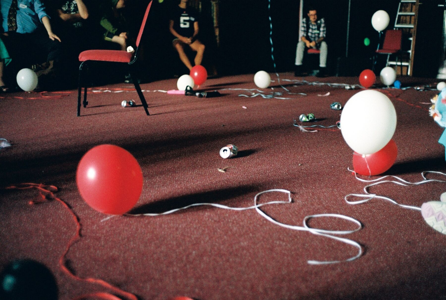 Røde og hvite ballonger på et rødt gulv. Det ser ut som det har vært fest. Foto.