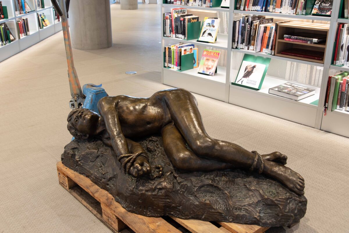 Skulptur på gulv stilt ut i bibliotek. Foto.