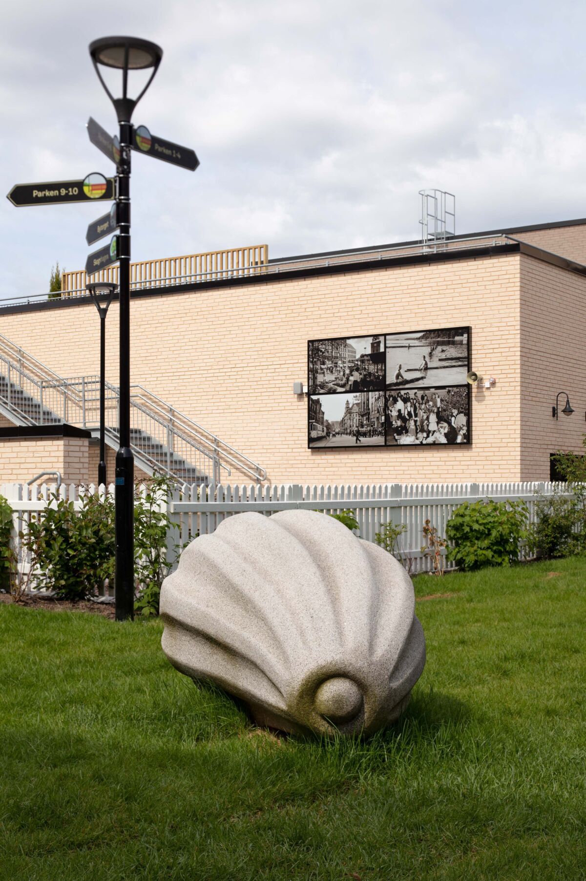 Skulptur av frø står på en gressplen. Foto.