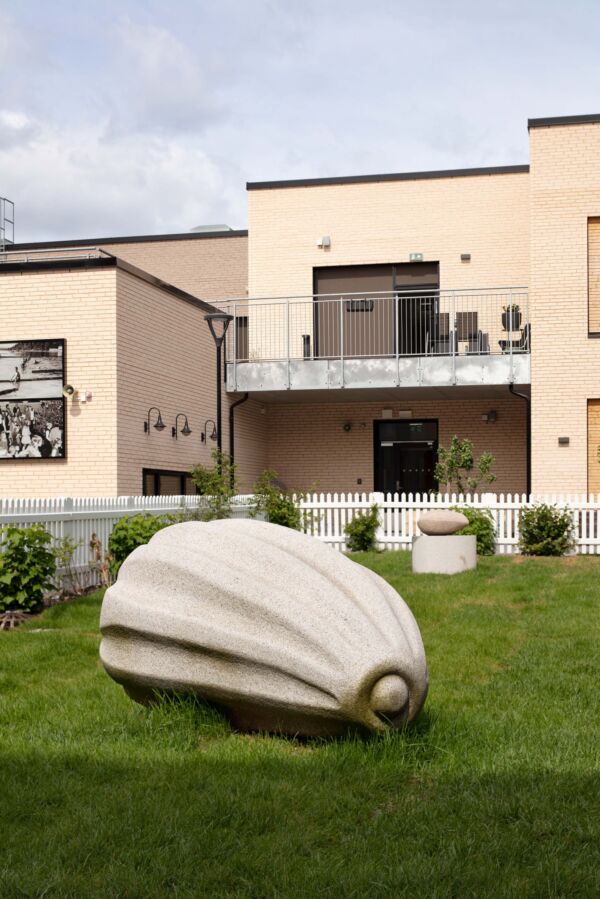 Skulptur av frø står på en gressplen. Foto.