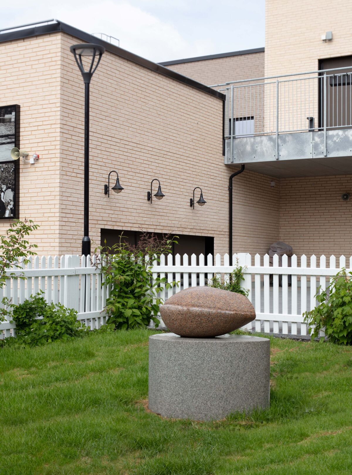 Skulptur av frø står på en gressplen. Foto.