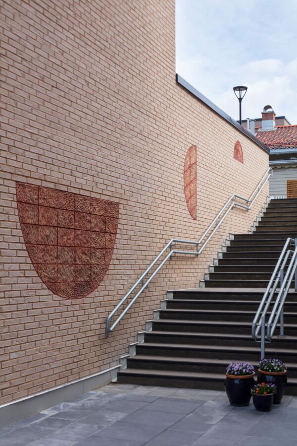 Keramiske halvsirkler integrert i en murvegg. Foto.