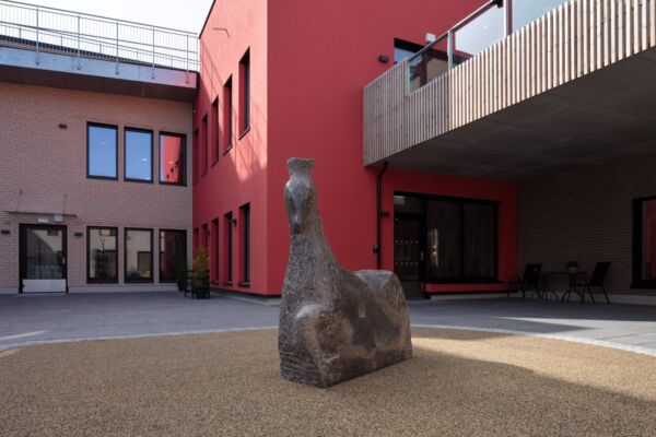 Skulptur av hest, omkranset av hus. Foto.