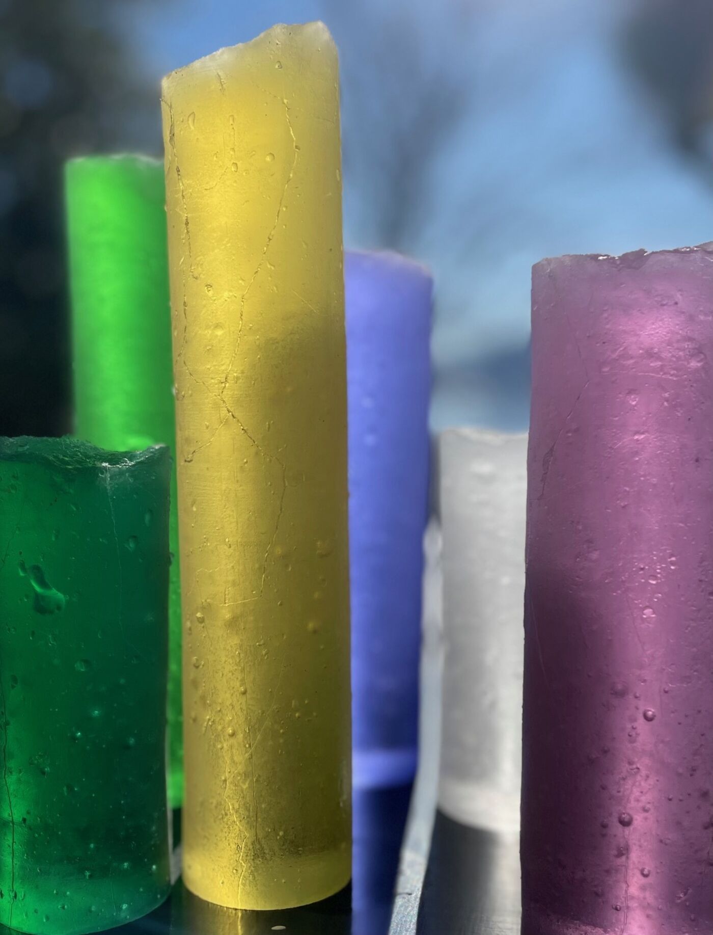Sylinderformet glass i ulike farger. Foto.