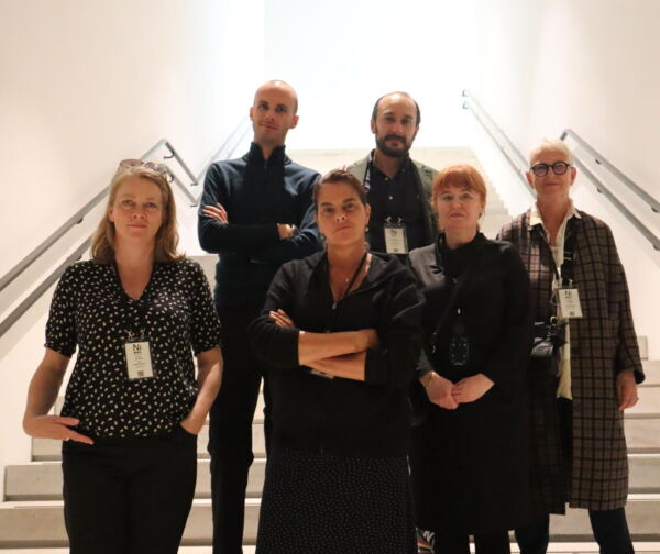 En gruppe mennesker står inne i en trapp og ser direkte i kamera.