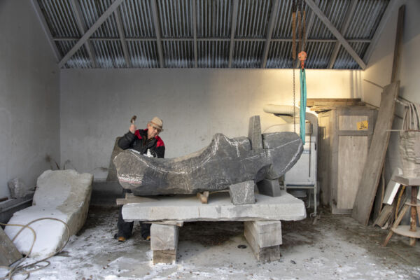 Kunstner Kristian Blystad hugger i stein i sitt uteatelier. Foto