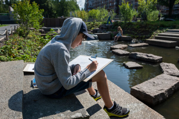 Foto av et barn som tegner i en tegneblokk i Klosterenga park.