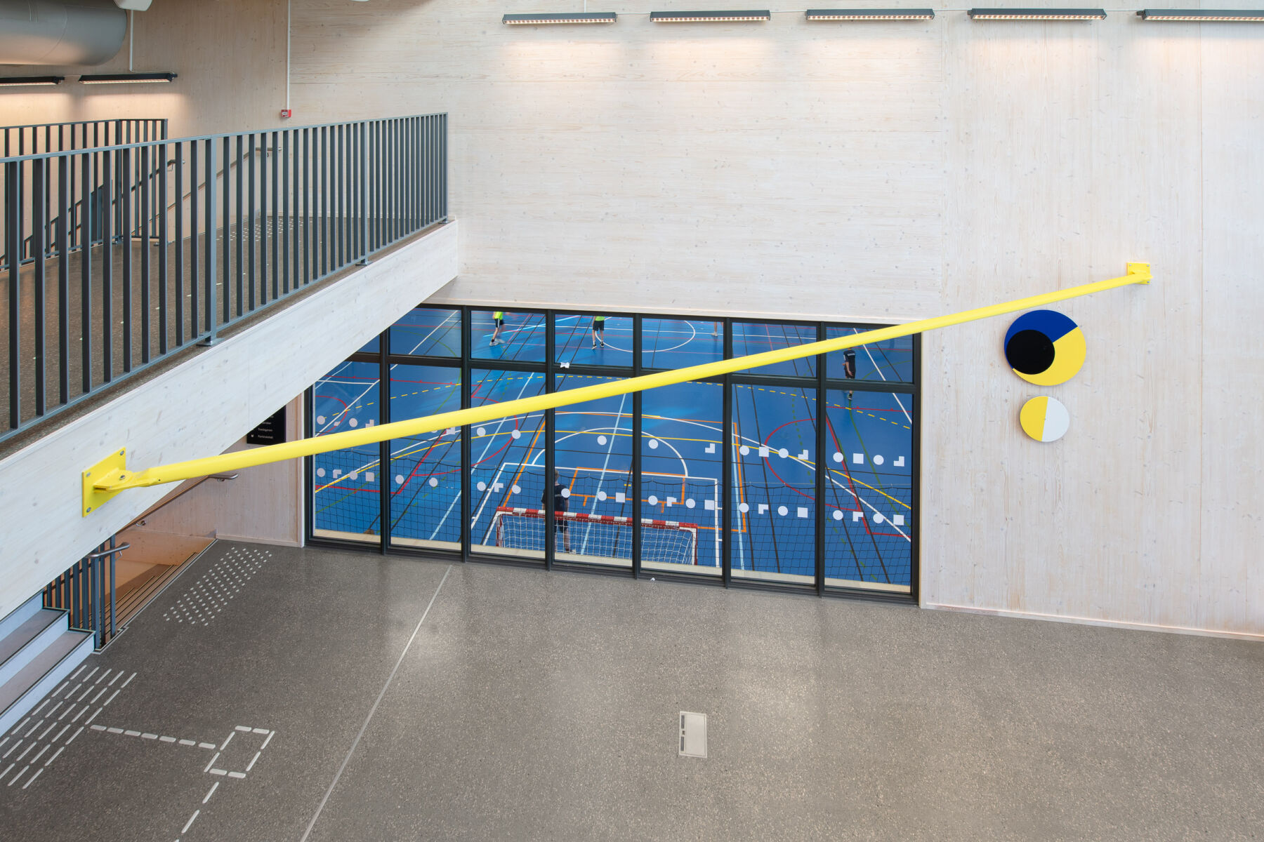 Geometriske veggskulpturer hengende innendørs. De har blå, gul, svart og hvit farge. Foto.