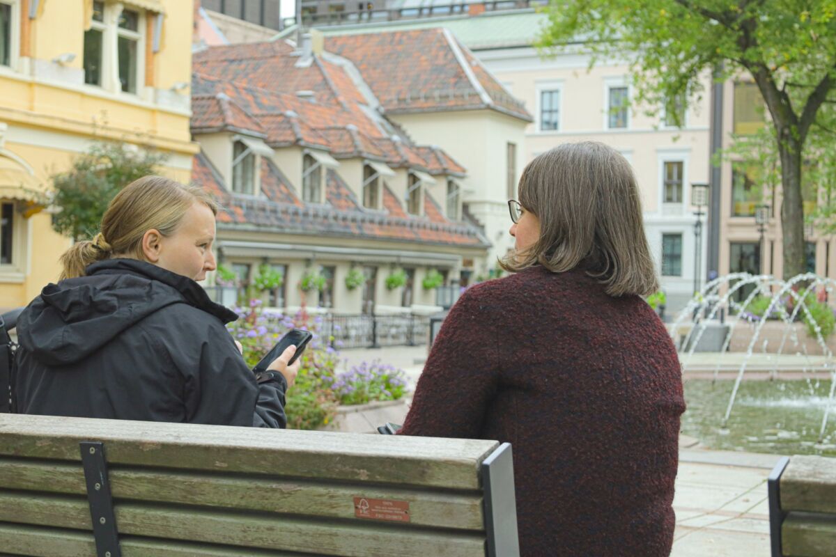 To personer sitter på benk ved fonteneanlegg på Bankplassen. Foto