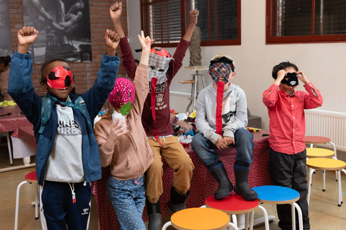 Fem barn i et verksted med masker på ansiktet. Foto.