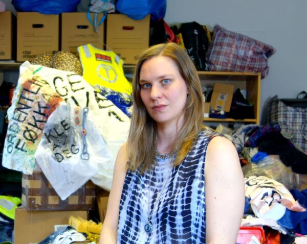 Person sitter foran mange pappesker, klær, poser og mer. Foto.