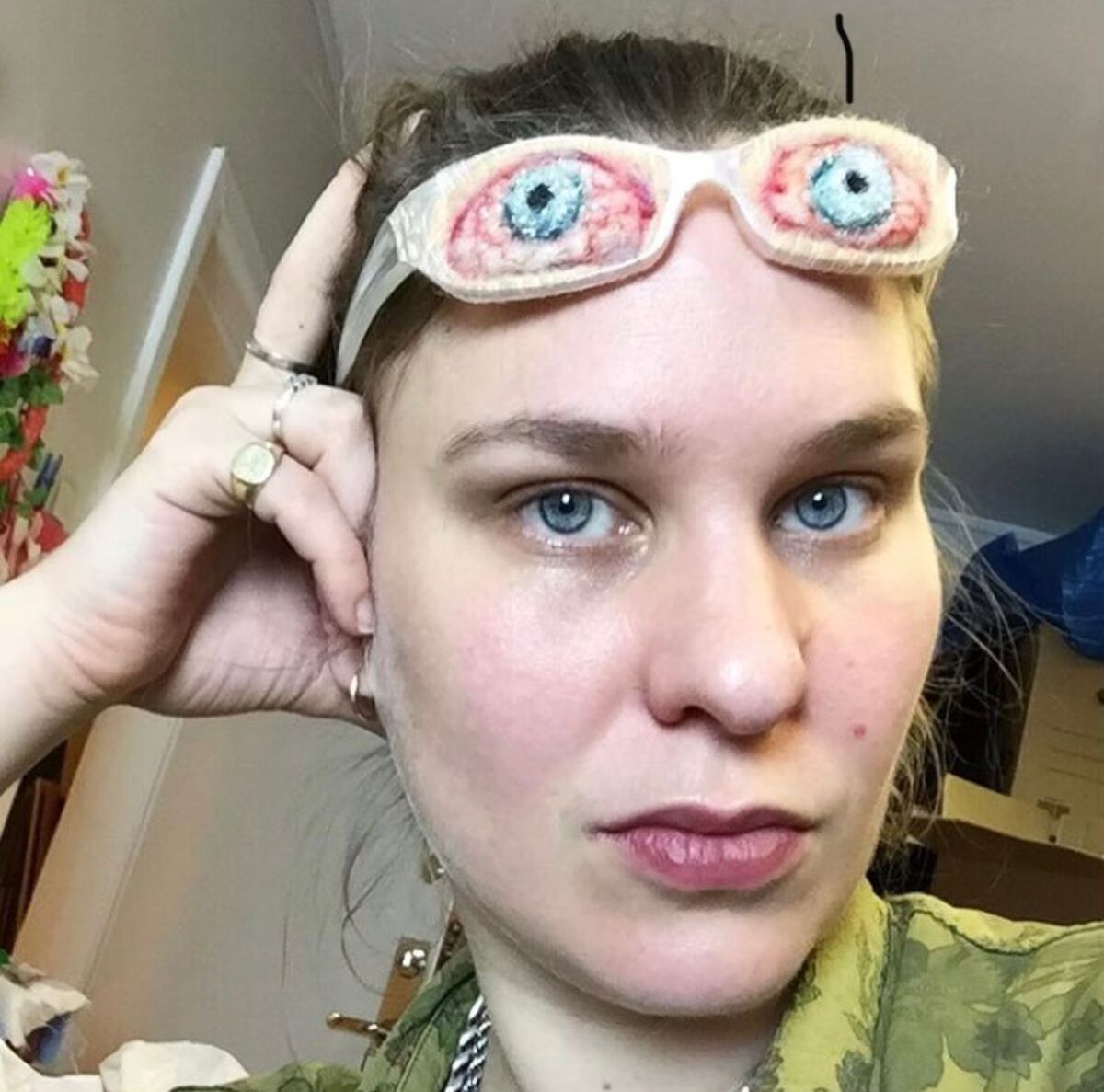 En person hviler hodet i hånda. På pannen har hun et par briller, laget av tekstil. Foto.