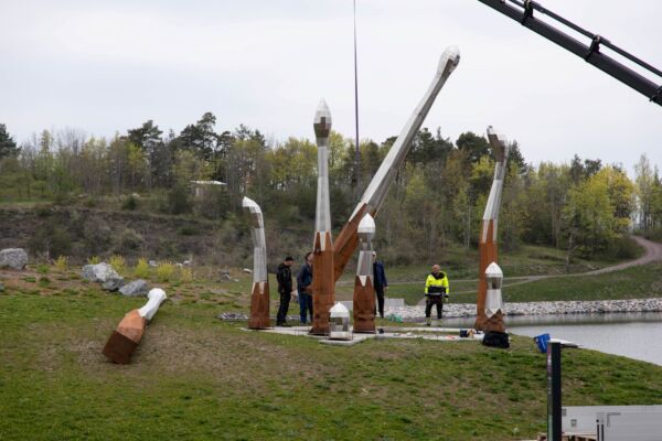Flere personer står blant en skulpturgruppe utendørs. Foto.