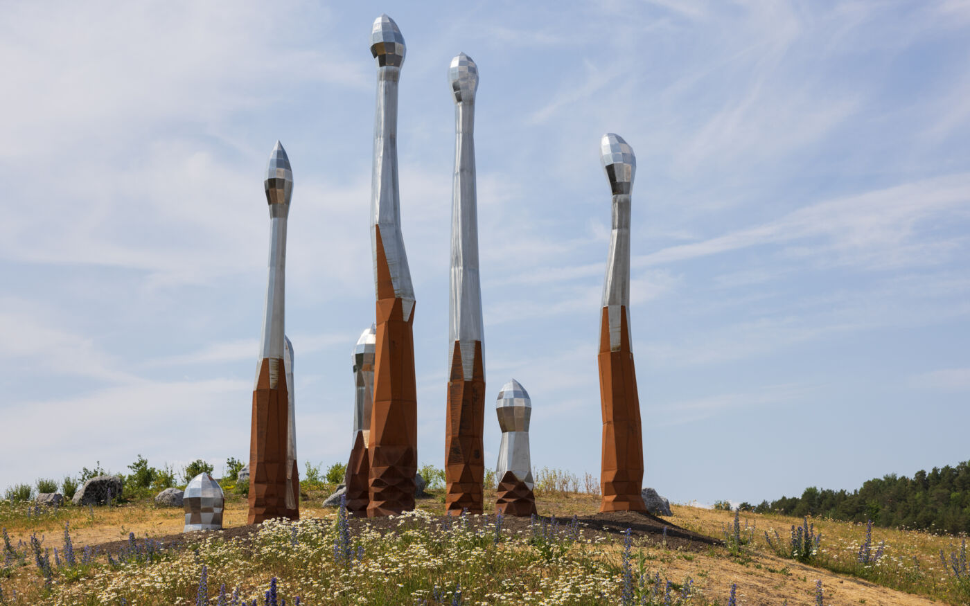 Spirelignende skulptur i grønt landskap. Foto.