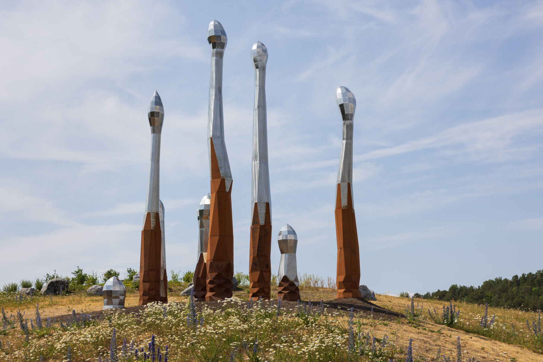 Spirelignende skulptur i grønt landskap. Foto.