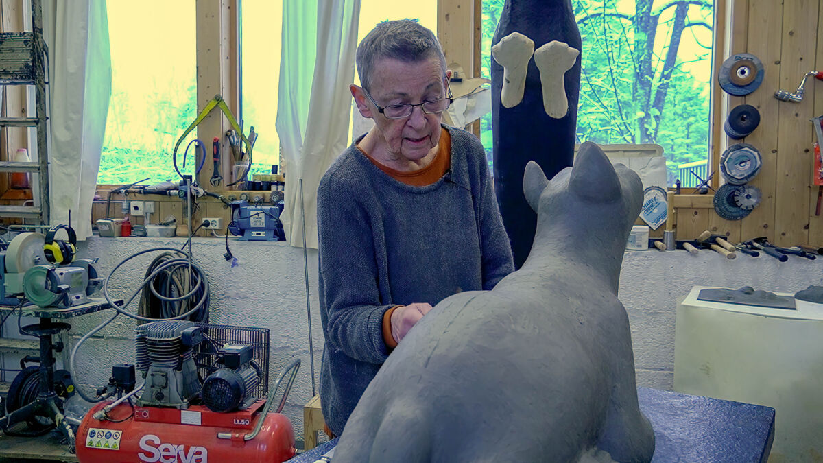 Person jobber med en løveskulptur i sitt atelier. Foto.