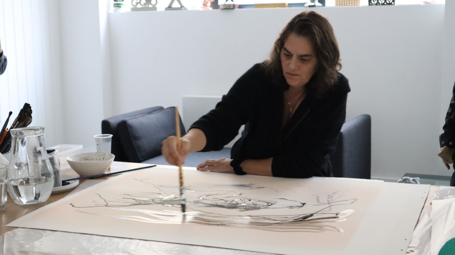 Kunstner sitter med pensel i hånden og maler. Foto