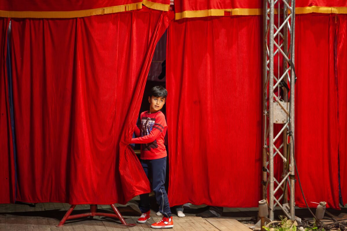 Barn står foran et rødt sceneteppe. Foto.