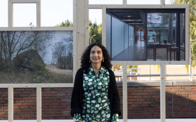 Person står foran en fotoutstilling montert på en sittebenk. Foto.