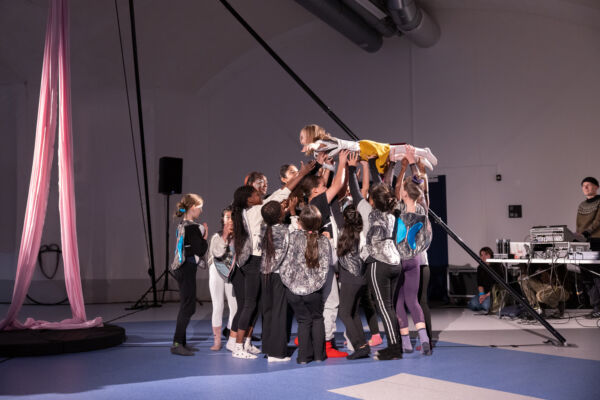 Mange barn på en scene under en forestilling. De turner. Foto.