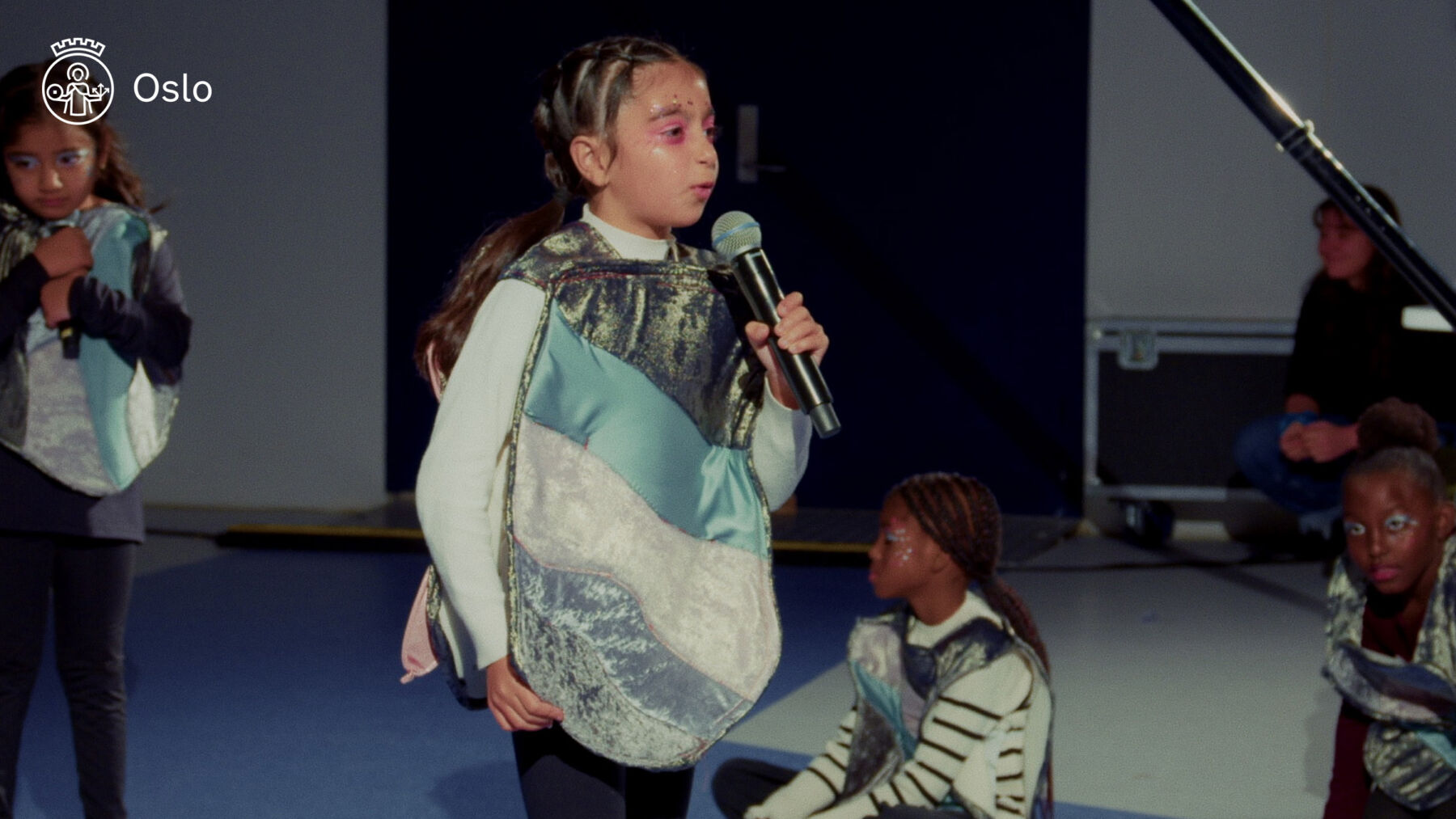 Skjermdump fra video av barn som synger i en mikrofon.