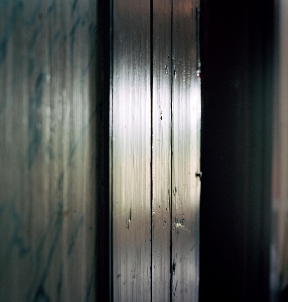 Nærbilde av panel i et mørkt rom med en stripe av lys som gir gjenskinn i trevirket. Foto.