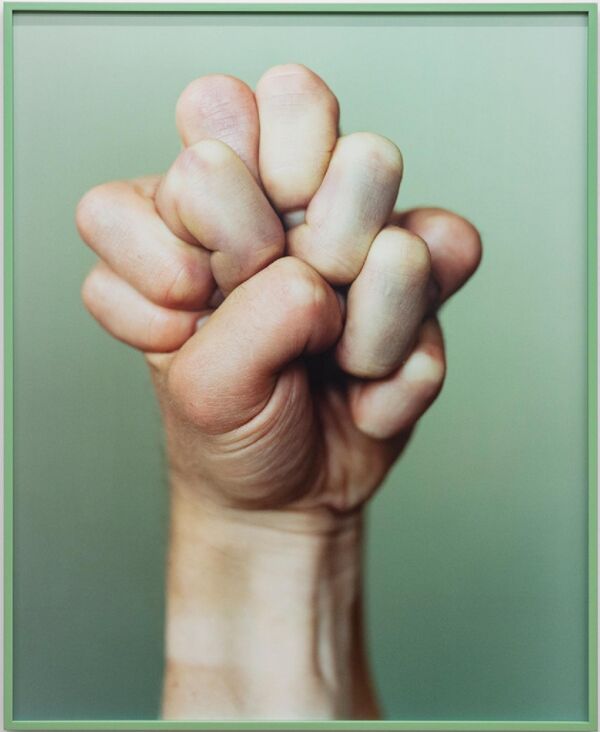 To hender som griper om hverandre. Bakgrunnen er lys grønn. Foto.