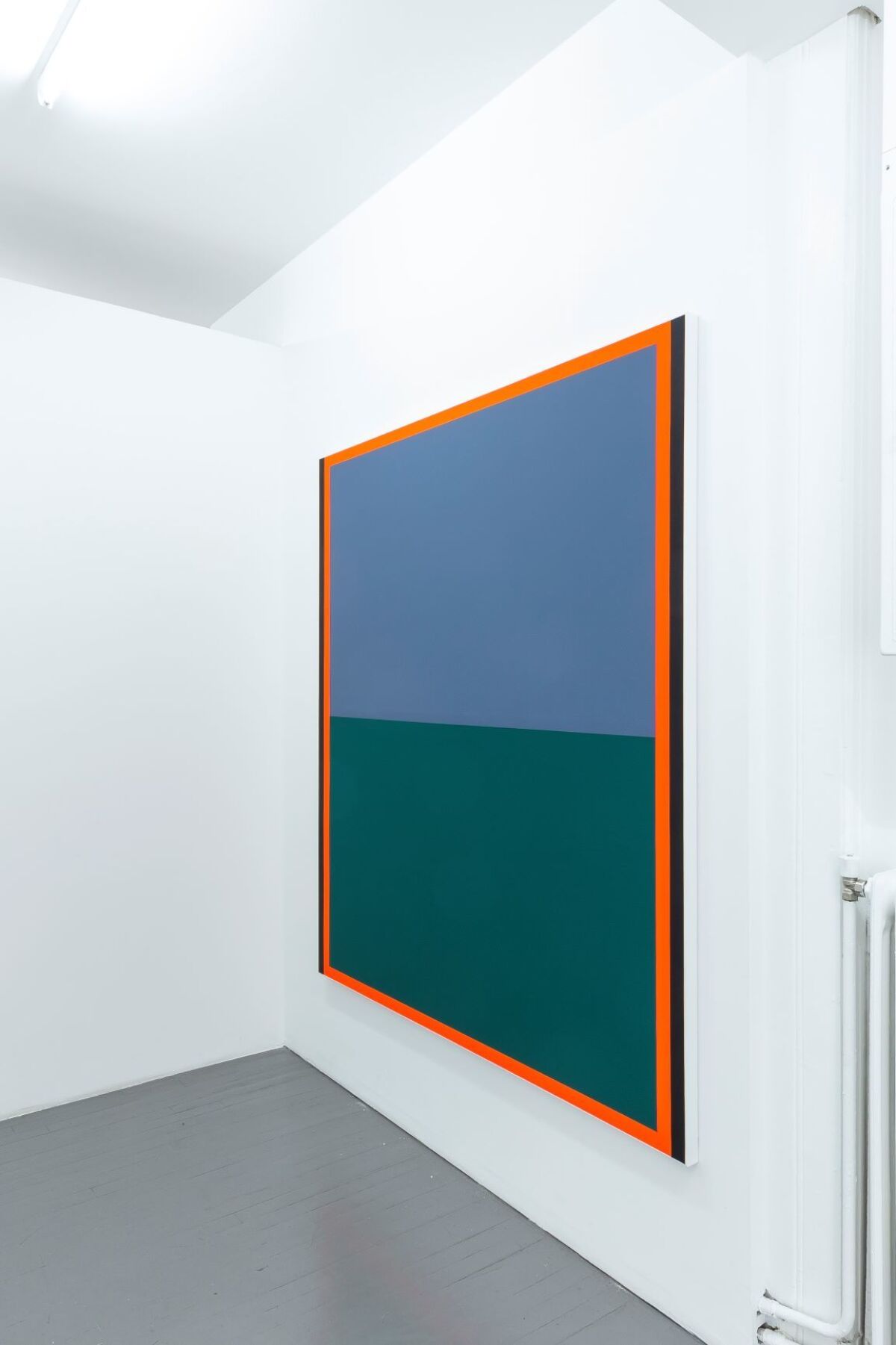 Et blått og grønt maleri med oransje ramme rundt henger på en hvit vegg. Foto.