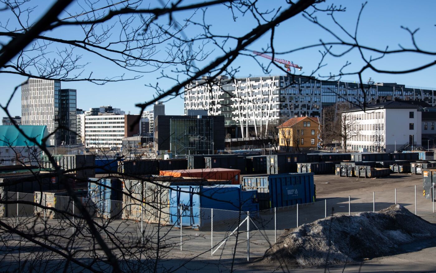 Oversiktsbilde over et område med containere, moderne kontorbygg og eldre trehus. Foto.