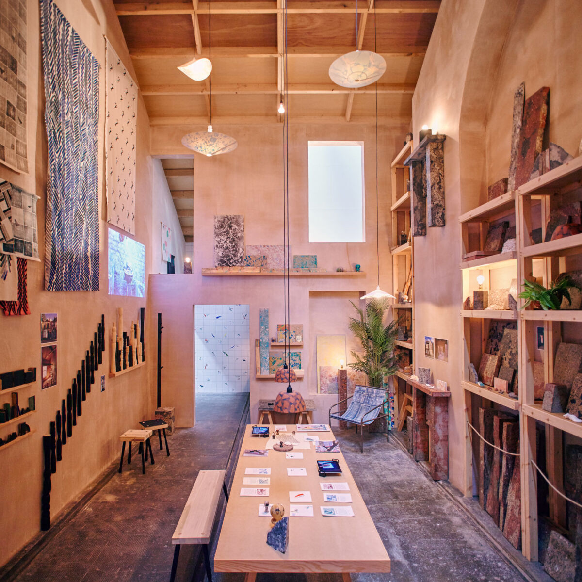 Et rom med langbord i midten, høyt under taket og ulike materialer og kunstverk hengende på veggen. Foto.