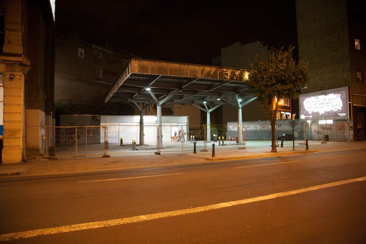 En nedlagt bensinstasjon på kvelden, fotografert fra andre siden av veien. Foto.
