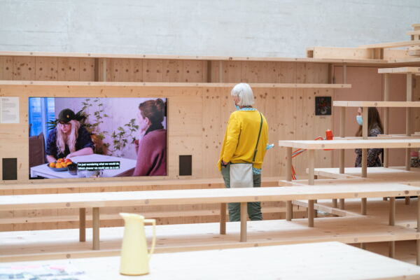 En person ser på en kunstvideo i et utstillingsrom. Foto.