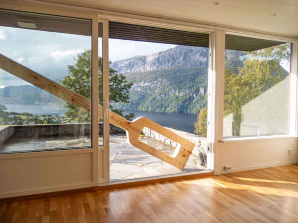 En stor treskulptur står på skrå foran en verandadør. Foto.