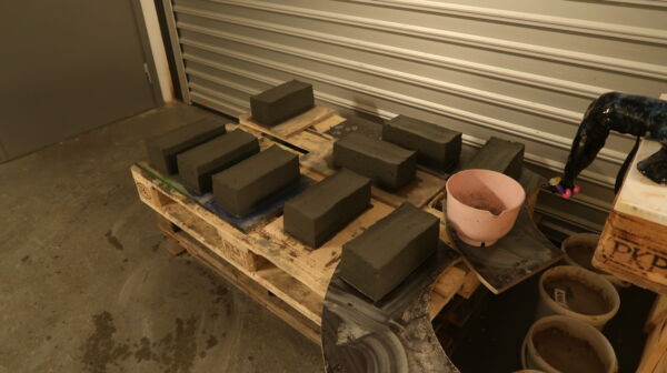 Flere mursteiner liggende innendørs på et verksted. Foto.