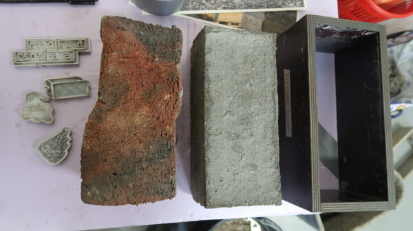 To mursteiner og en mursteinsform liggende på et bord. Foto.