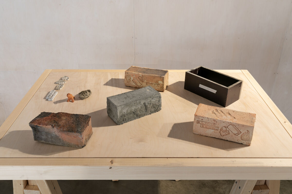 Et lyst bord med murstein i ulike stadier liggende på. Bildet viser hvordan murstein blir til. Foto.