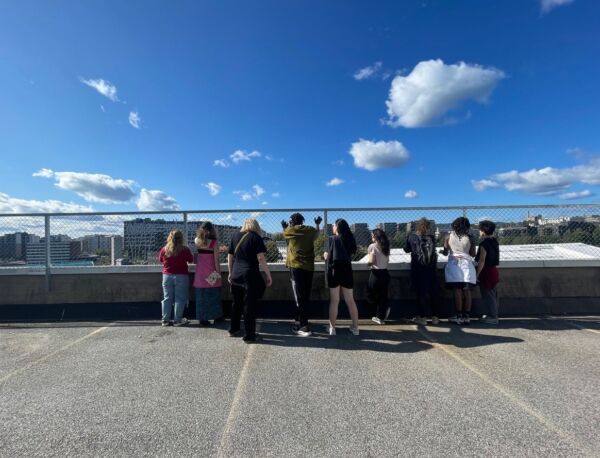 Åtte mennesker ser utover horisontene. De er fotografert bakfra. Foto.