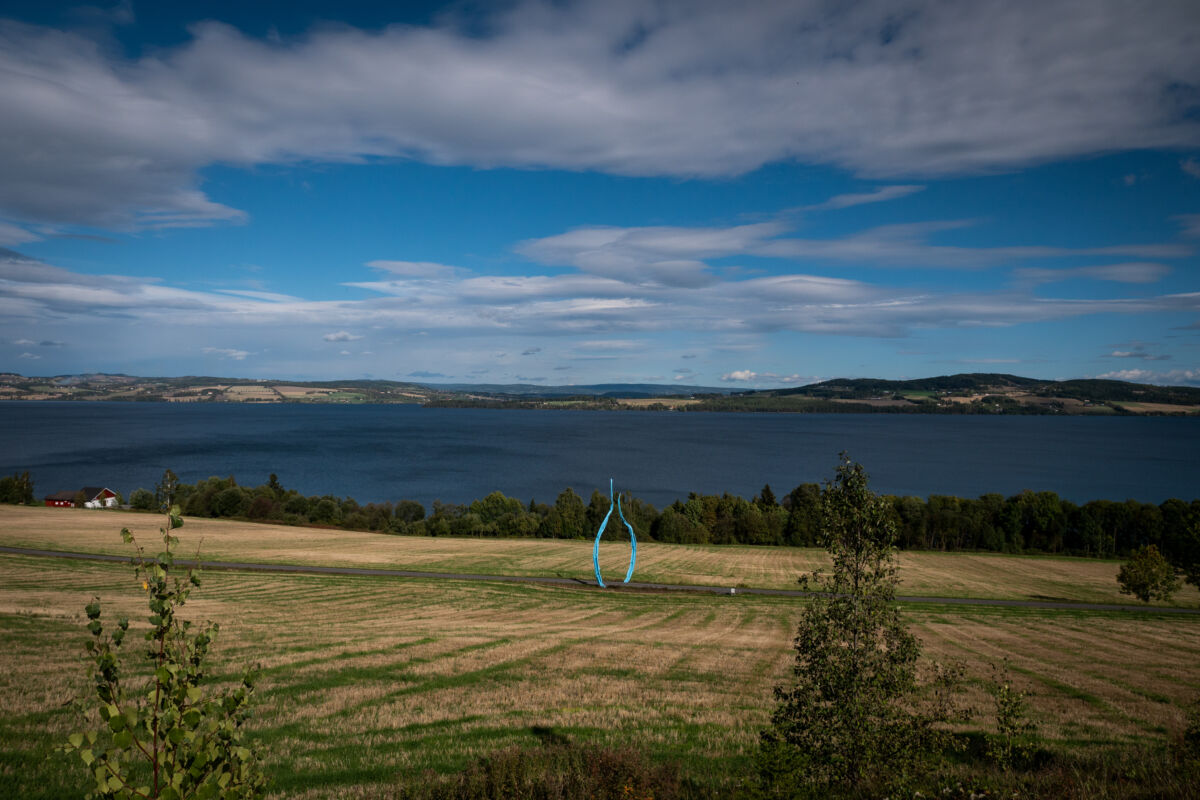 Rund, blå skulptur stående på et jorde. Foto.