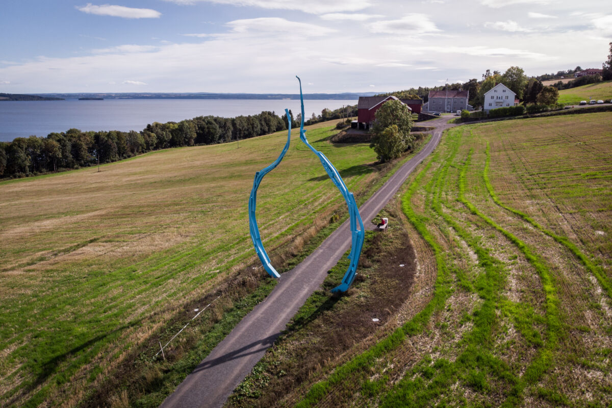 Rund, blå skulptur stående på et jorde. Foto.