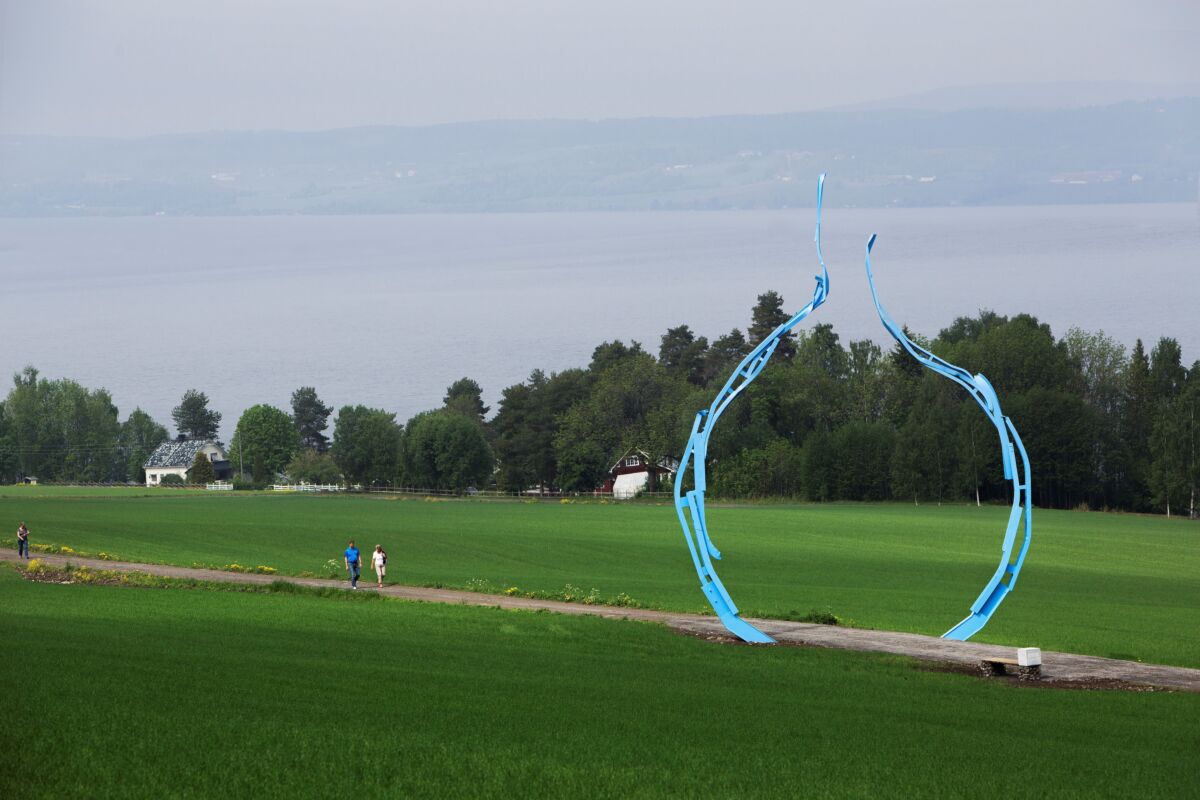 Rund, blå skulptur stående på et jorde. Foto.