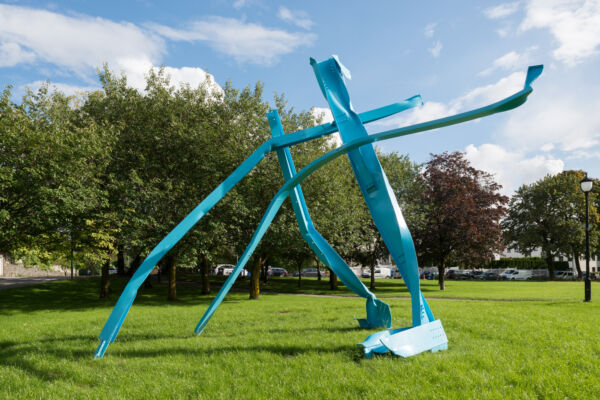 Foto av en blå skulptur stående ute i grønne omgivelser.