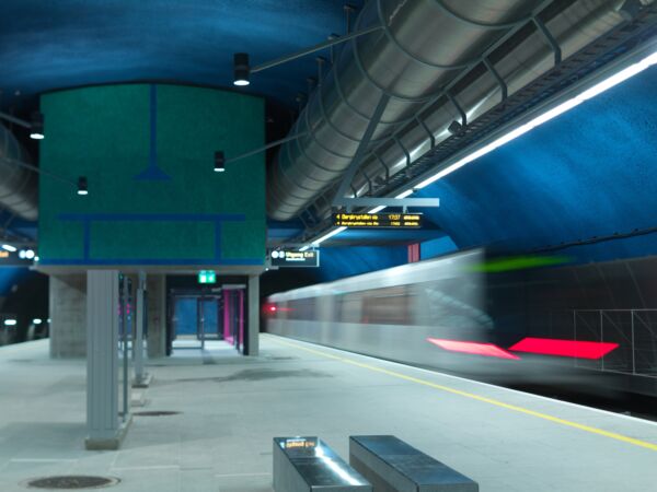 Foto av et blått veggmaleri innendørs på en t-banestasjon.