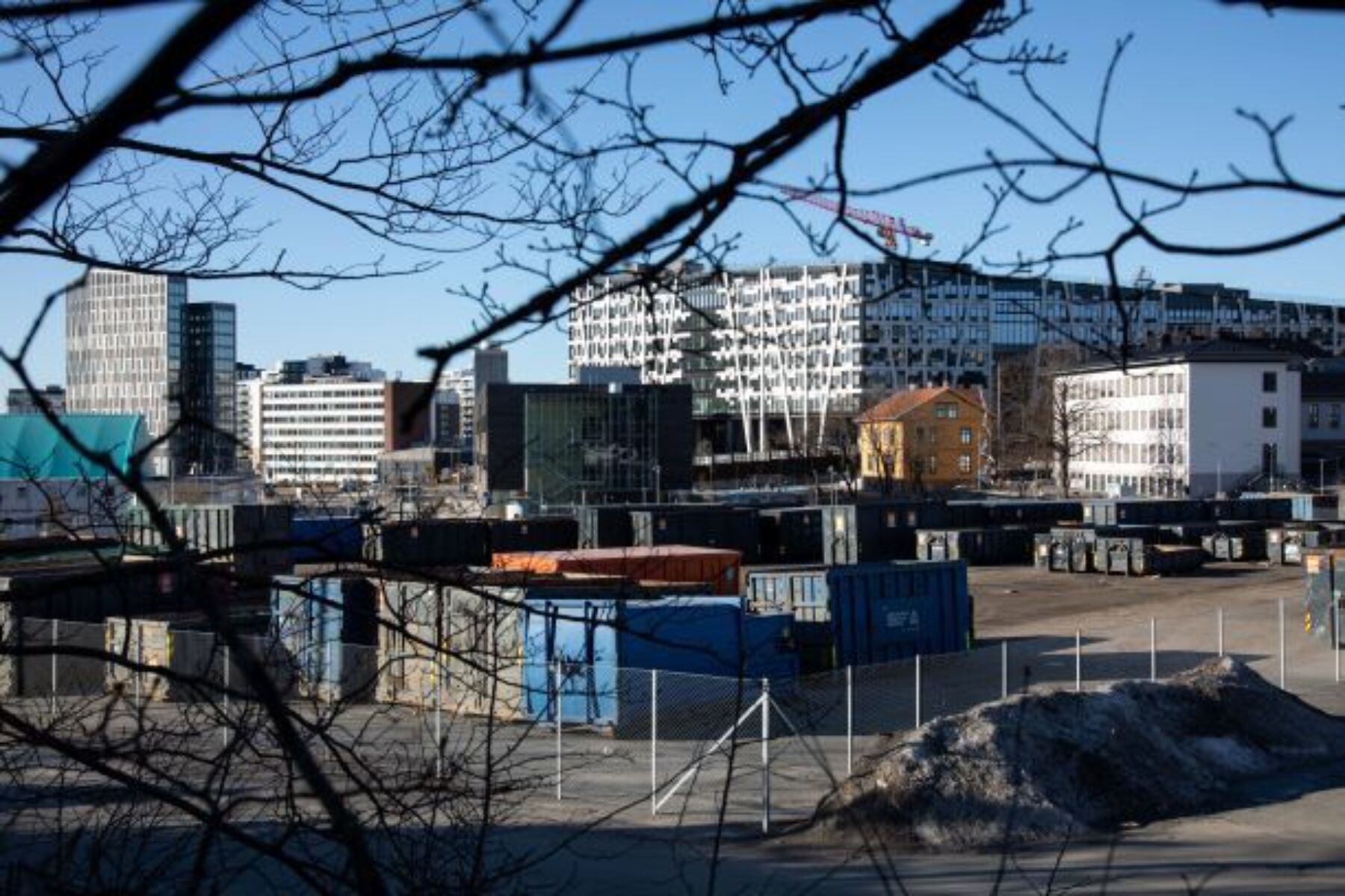 Oversiktsbilde over et område med containere, moderne kontorbygg og eldre trehus. Foto.