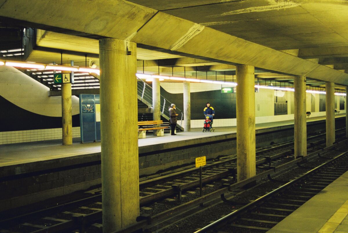 Interiør av en t-banestasjon. Flere mennesker går på perrongen. Foto.